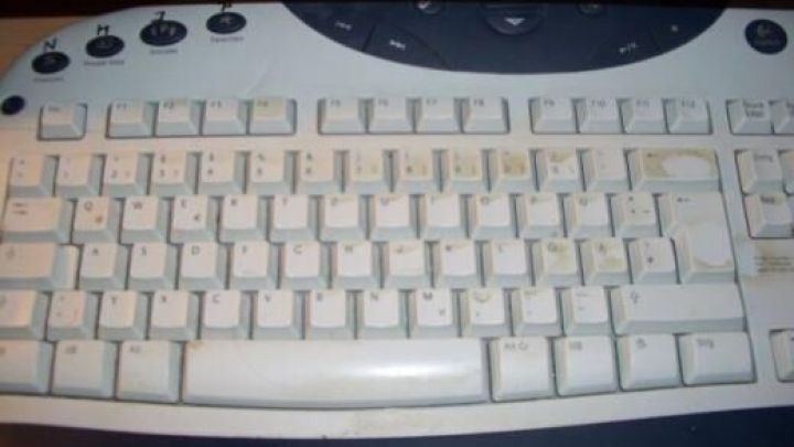 Die Computer-Tastatur, leicht verschmutzt und verstaubt, liegt auf einem dunklen Tisch, ohne sichtbare Klarsichtfolie.