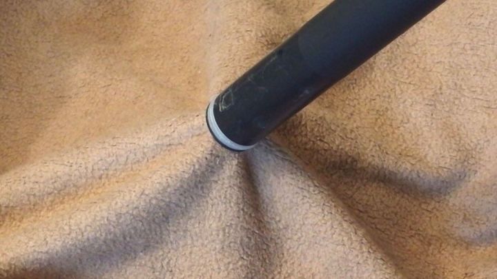 Der Staubsauger saugt an einem weichen, braunen Stoff, der Falten wirft und die Saugkraft verdeutlicht.