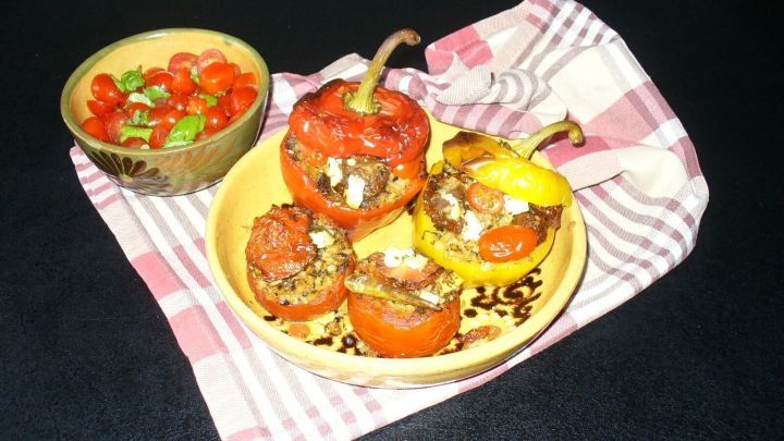 Gef&uuml;llte Paprika aus verschiedenen Farben liegen auf einem Teller, neben einer Sch&uuml;ssel mit frischer Tomatensalsa.