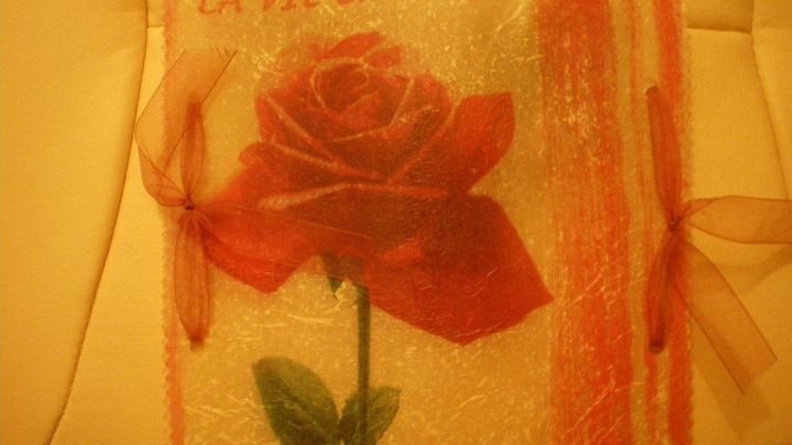 Ein laminiertes Windlicht mit einer roten Rose und dem Text &bdquo;LA VIE EN ROSE&ldquo; auf einem weichen Hintergrund.