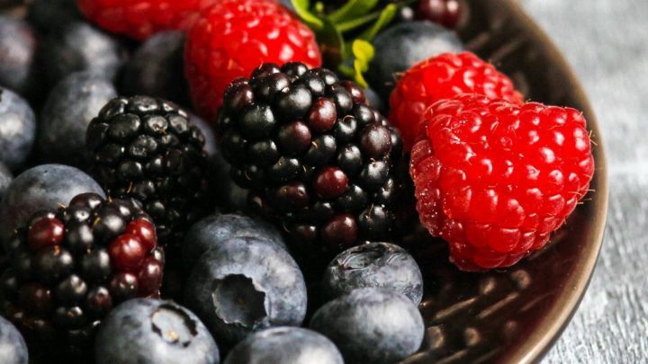 Frische Beeren liegen in einer Sch&uuml;ssel und zeigen eine Vielzahl von Obstflecken, die m&ouml;glicherweise mit Milch behandelt werden k&ouml;nnen.