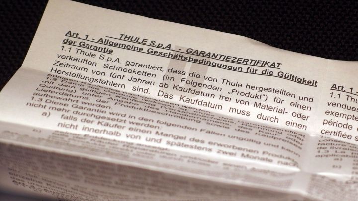 Ein gefaltetes Dokument liegt auf einer dunklen Oberfl&auml;che und enth&auml;lt Informationen &uuml;ber Garantiebedingungen bei Internetk&auml;ufen.