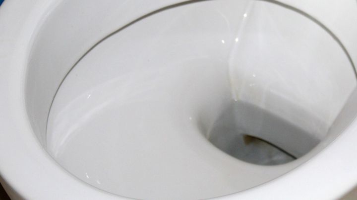 Eine Toilette zeigt Kalkablagerungen im inneren Bereich, die sich in einem sauberen Badezimmer befinden.