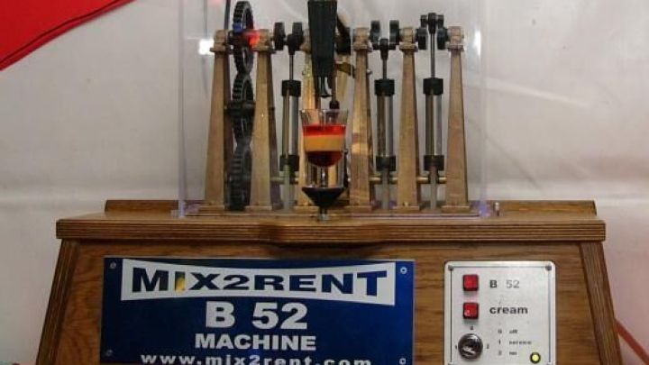 Eine Maschine mit Aufschrift "MIX2RENT B 52 MACHINE" mixt Getr&auml;nke automatisch. Steuerkn&ouml;pfe: B 52, cream. Webseite: www.mix2rent.com.