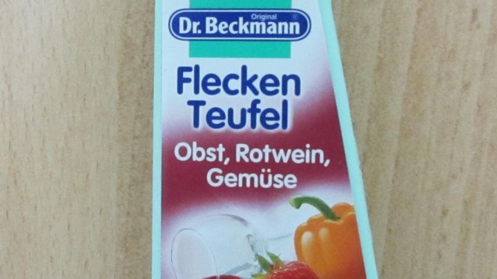 Eine Flasche Dr. Beckmanns Fleckenteufel steht auf einem hellen Tisch. Sie behandelt Flecken von Obst, Rotwein und Gem&uuml;se.