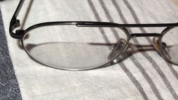 Brille liegt auf gestreiftem Handtuch; metallener Rahmen reflektiert Licht.