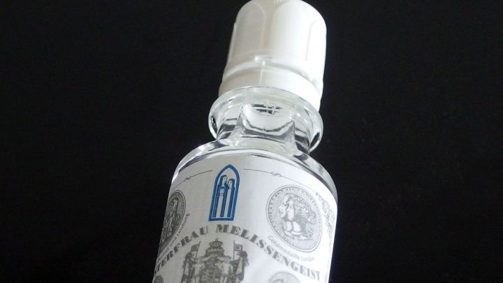 Ein Glasfl&auml;schchen mit Melissengeist steht auf einem dunklen Hintergrund, bereit zur Vorbeugung gegen Pickel.