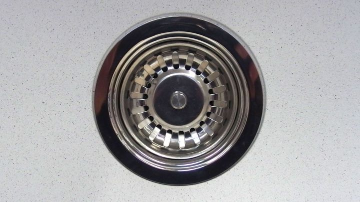 Ein Abfluss mit einem silbernen Sieb in einer modernen K&uuml;chenarbeitsplatte, bereit f&uuml;r die Reinigung mit Sp&uuml;lmaschinenpulver.