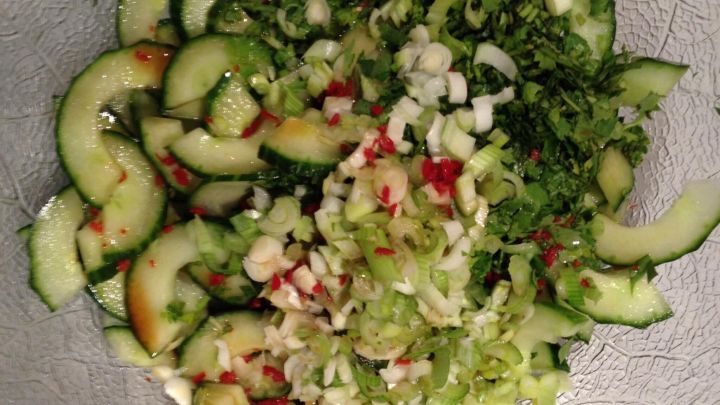 Frisch geschnittener Gurkensalat liegt in einer Sch&uuml;ssel, gemischt mit Kr&auml;utern und frischen Zutaten.