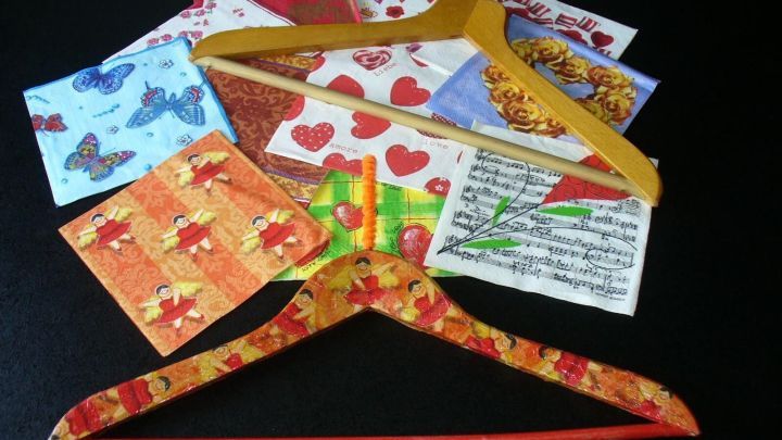 Bunte Holzkleiderb&uuml;gel liegen auf einem Tisch, umgeben von dekorativem Papier, bereit zum Versch&ouml;nern und Gestalten.