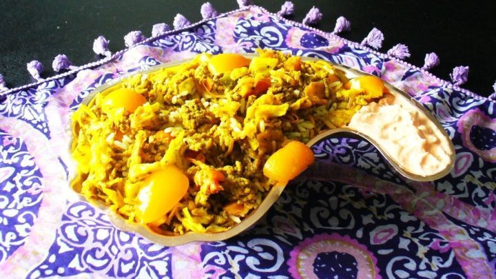 Eine schmackhafte indische Mett-Reis-Pfanne liegt auf einem bunten Teller, umgeben von einem dekorativen, gemusterten Tuch.