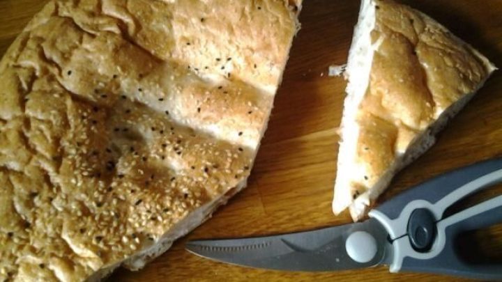 Ein Satz Gefl&uuml;gelscheren schneidet ein St&uuml;ck Brot auf einer Holzoberfl&auml;che, um ihre vielseitige Verwendung zu zeigen.