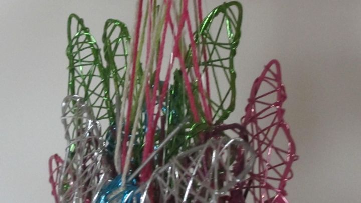 Bunte Dekoh&auml;nger h&auml;ngen zusammen, w&auml;hrend sie an einem ringf&ouml;rmigen Halter angebracht sind, um ein Verknoten zu verhindern.