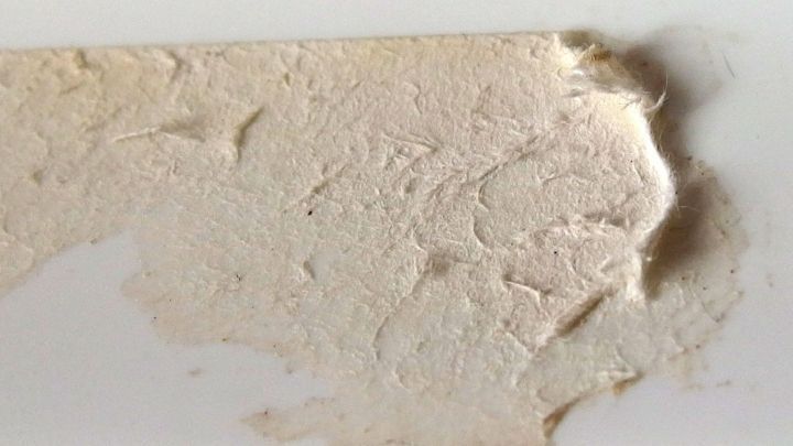 Ein St&uuml;ck Papier zeigt Kleberreste, die durch Tesafilm entfernt werden sollen. Die Oberfl&auml;che wirkt unregelm&auml;&szlig;ig und staubig.