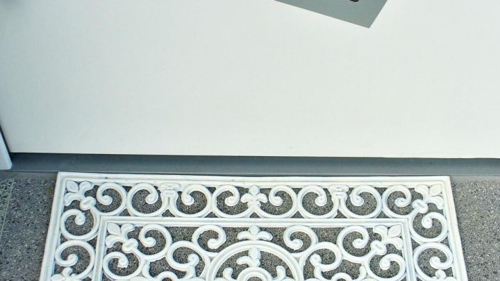 Eine kunstvoll verzierte Gummifu&szlig;matte liegt vor einer modernen Haust&uuml;r und verleiht dem Eingangsbereich Eleganz.