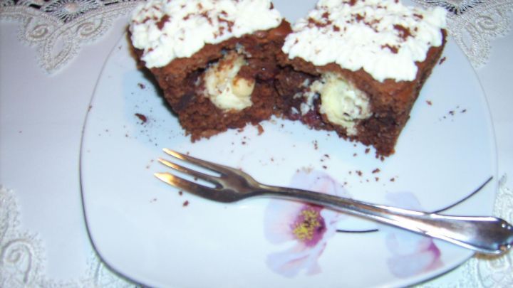 Zwei Schokok&uuml;chlein liegen auf einem Teller, gef&uuml;llt mit einer cremigen Kokosf&uuml;llung und garnieren mit Sahne.