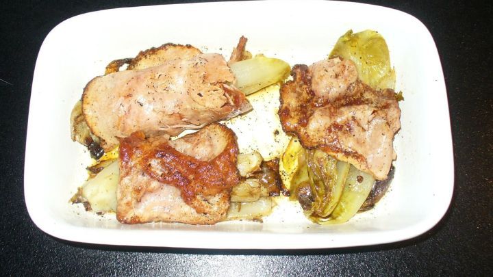 Ein Teller zeigt Chicoree, umh&uuml;llt von Schinken und K&auml;se, zusammen mit goldbraun gebratenen Kartoffeln, appetitlich angerichtet.