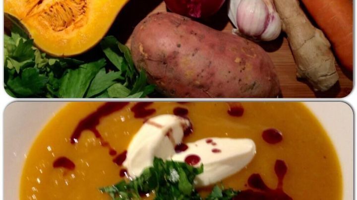 Eine cremige K&uuml;rbiscremesuppe mit S&uuml;&szlig;kartoffeln wird in einer Schale serviert, umgeben von frischem Gem&uuml;se und Kr&auml;utern.