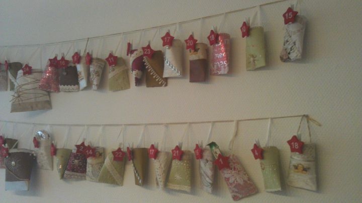 Papierrollen sind aufgeh&auml;ngt, nummeriert als Adventskalender, an einer Wand mit dekorativen Rotsternen von 1 bis 24.