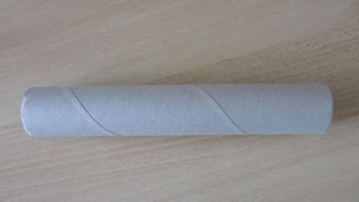 Eine Toilettenrolle liegt auf einem Tisch und wird zur Geschenkverpackung umgestaltet, um kreativ zu verpacken.