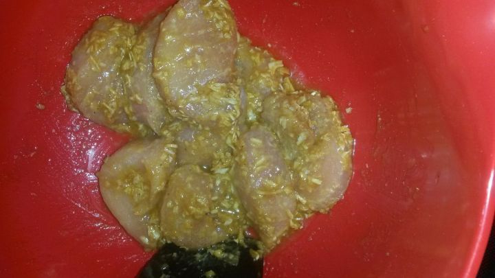 Fleischst&uuml;cke mariniert in einer gelben Sauce liegen in einer roten Sch&uuml;ssel. Ein schwarzer L&ouml;ffel steckt darin.