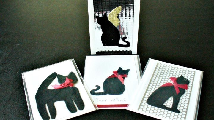 Schwarze Gru&szlig;karten mit Katzenmotiven und roten Schleifen stehen dekorativ auf einem Tisch, bereit zum Verschenken.