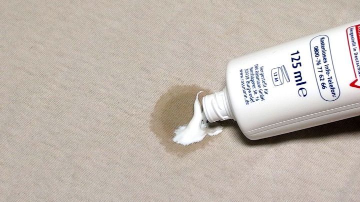 Eine Zahnpasta wird auf einen Obstfleck auf einem hellen Stoff aufgetragen, um den Fleck zu entfernen.