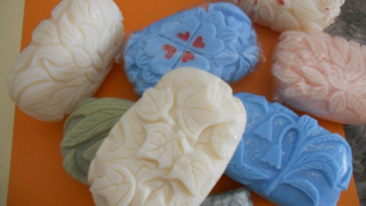 Kunstvoll gestaltete Seifen mit filigraner Seifenschnitzerei liegen auf einer orangefarbenen Fl&auml;che.