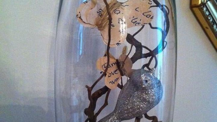 Eine Glasvase enth&auml;lt zarte Schmetterlinge und geschlungene &Auml;ste, umgeben von einem gr&uuml;nen Moosboden.