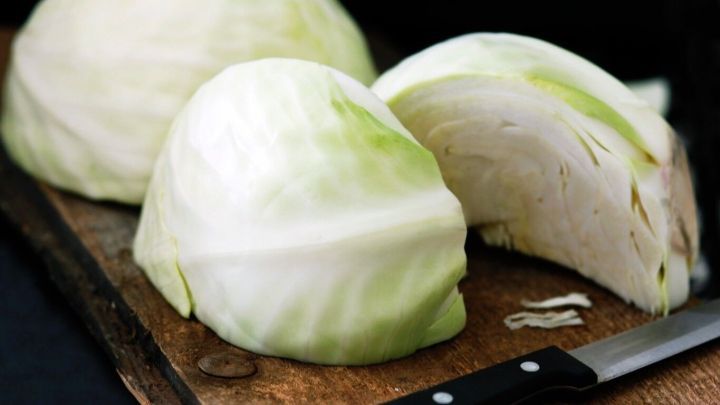 Frischer Wei&szlig;kohl liegt auf einem Holzbrett, ein Teil ist geschnitten, w&auml;hrend ein Messer daneben liegt.