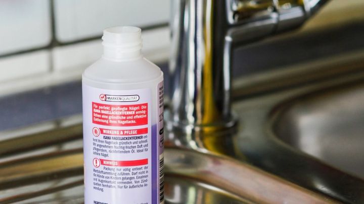 Eine Flasche Reinigungsmittel steht neben einem Wattepad auf einer Sp&uuml;le, bereit zum Armaturen reinigen in der K&uuml;che.