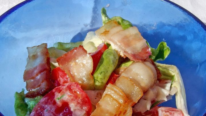 Ein bunter Salat mit frischem Gem&uuml;se und warmen Zutaten in einer blauen Sch&uuml;ssel, ideal f&uuml;r eine warme Salatso&szlig;e.