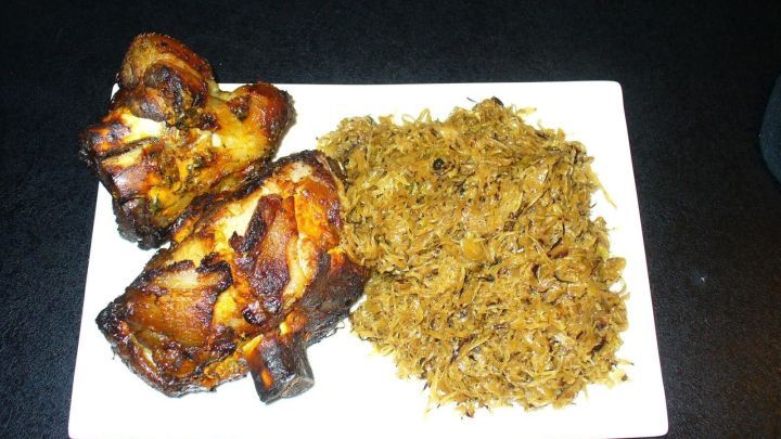 Zwei knusprige, zarte Grillhaxen liegen auf einem wei&szlig;en Teller neben einer Portion w&uuml;rzigem Reis.