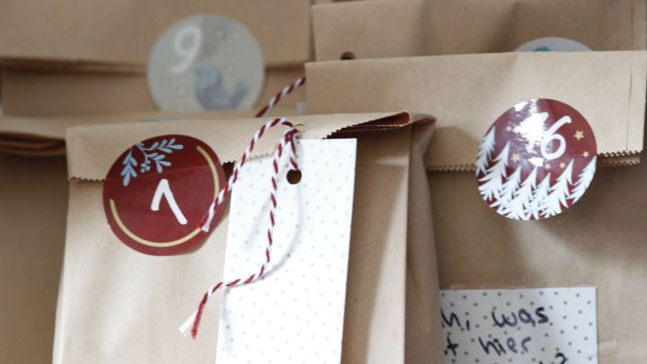 Papiert&uuml;ten mit Zahlen und personalisierten Anh&auml;ngern stehen in einer Gruppe, bereit f&uuml;r einen DIY-Adventskalender.