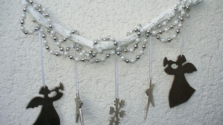 Eine bezaubernde Weihnachtsdekoration mit silbernen Perlen und schwarzen Engeln h&auml;ngt an einer Wand und verleiht festliche Stimmung.