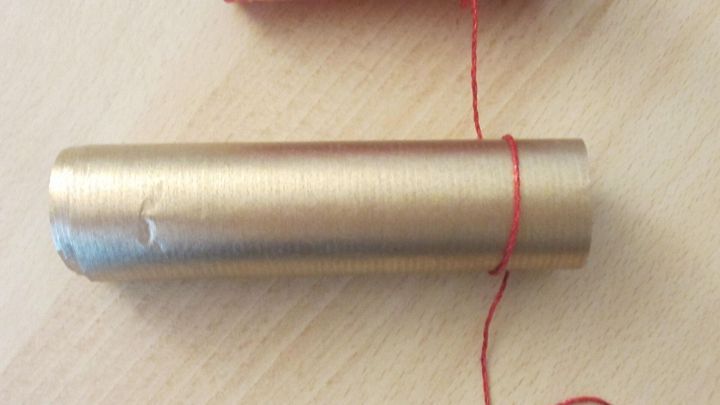 Bunte Papierrollen werden auf einem Tisch nebeneinander angeordnet, um einen festlichen Tannenbaum zu formen.