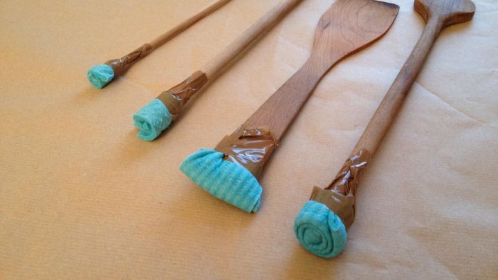 Selbstgemachte Pinsel aus Kochl&ouml;ffeln und Schwammt&uuml;chern stehen auf einem Tisch, bereit zum Malen oder Dekorieren.