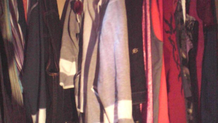 Im Schrank h&auml;ngen verschiedene Kleidungst&uuml;cke, einschlie&szlig;lich grauer und roter Jacken, dicht beieinander.