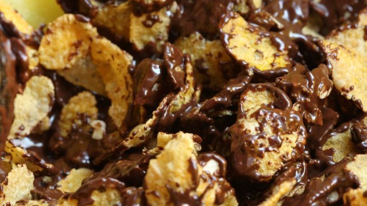 Knusprige Cornflakes-Klumpen, &uuml;berzogen mit geschmolzener Schokolade, liegen dicht zusammen.