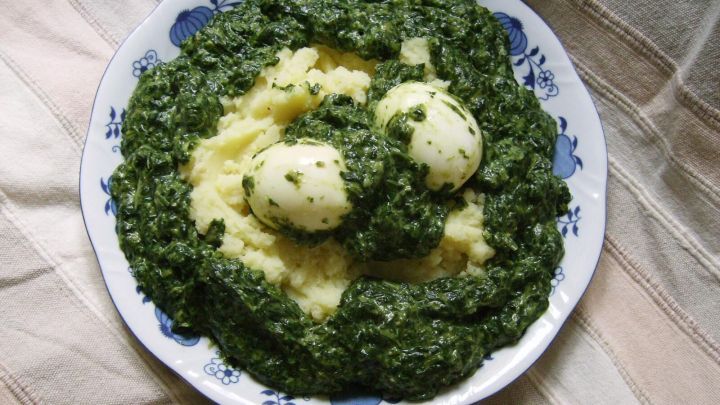 Zwei Eier liegen auf cremigem Kartoffelp&uuml;ree, &uuml;berzogen mit frischem Spinat. Der Anblick ist appetitlich und s&auml;ttigend.