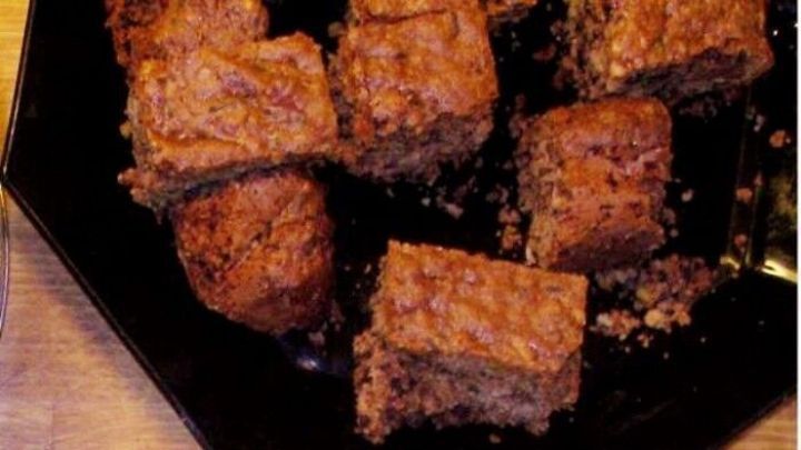 Saftige Brownies liegen auf einem schwarzen Teller, unregelm&auml;&szlig;ig zugeschnitten und appetitlich angerichtet.