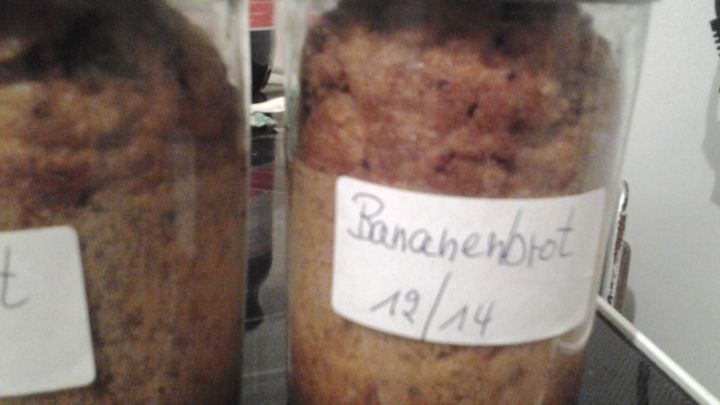 Zwei Sturzgl&auml;ser enthalten frisch gebackenes Bananenbrot, etikettiert und in einer K&uuml;chenumgebung platziert.