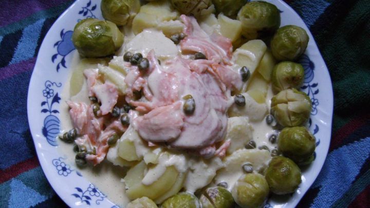 Ein Teller mit gebackenem Lachsforellenfilet in einer Senf-Meerrettich-So&szlig;e, umgeben von Bratkartoffeln und gr&uuml;nen Bohnen.