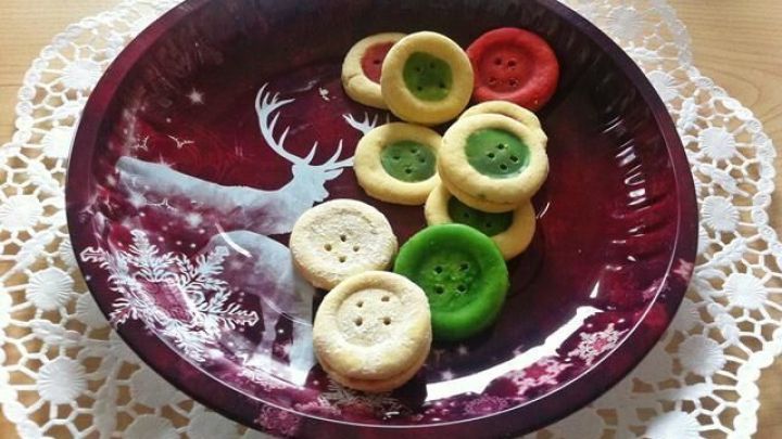 Auf einem roten Teller mit Spitze liegen farbige Knopfpl&auml;tzchen in verschiedenen Farben, die festlich arrangiert sind.