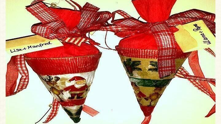 Zwei dekorativ verpackte Naschereien in Kegelform, geschm&uuml;ckt mit rotem Geschenkband und Etiketten.