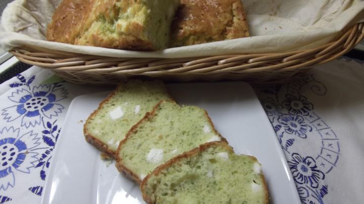 Feta-Kuchen mit Kr&auml;utern liegt in einem Korb, w&auml;hrend geschnittene St&uuml;cke auf einem Teller serviert werden.