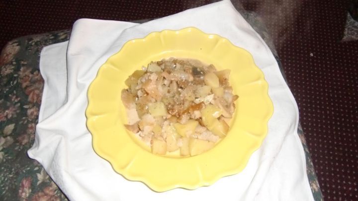 Ein Teller mit dampfender Blumenkohlpfanne, serviert in einer gelben Schale auf einem wei&szlig;en Tuch, ist zu sehen.