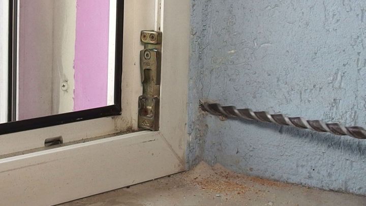 Ein Bohrer wird an einer Wand nahe einem Fenster angesetzt, um zu verhindern, dass zu tief gebohrt wird.