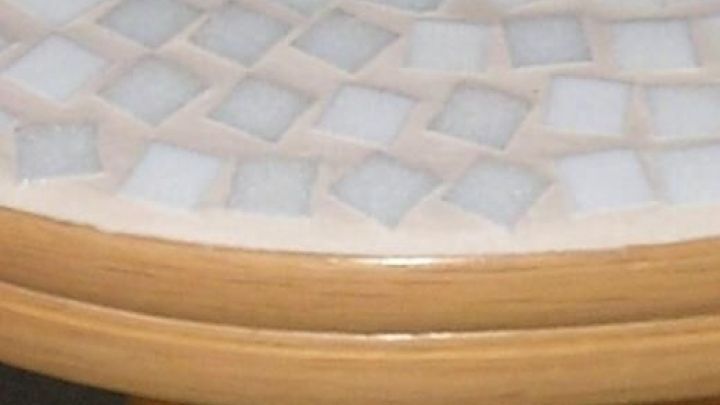 Ein Holztisch mit einem h&uuml;bschen Mosaikmuster dekoriert, steht in einem hellen Raum und verleiht eine warme Atmosph&auml;re.