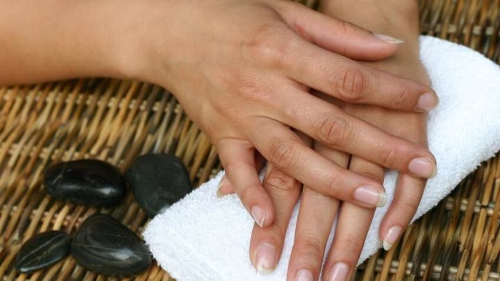 H&auml;nde liegen auf einem wei&szlig;en Handtuch, w&auml;hrend sie sich auf eine entspannende Handpeeling-Anwendung vorbereiten.